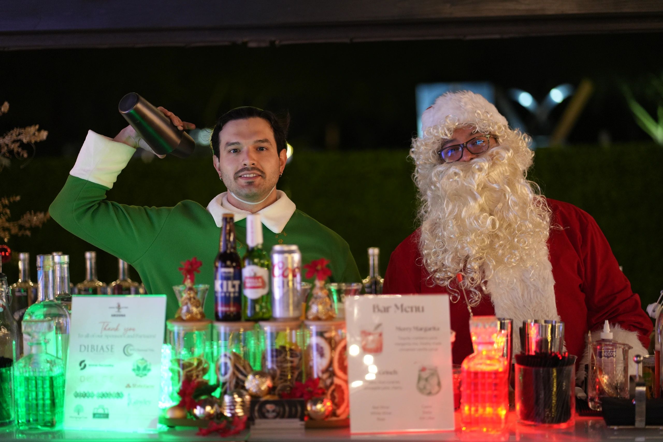 Santa Claus and a bartender serving holiday drinks at the event bar